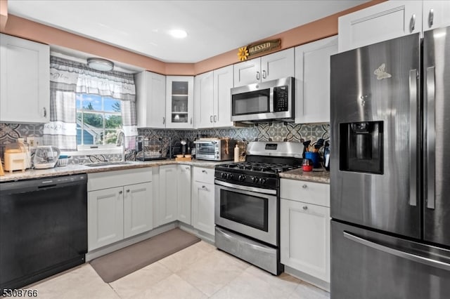 kitchen featuring appliances with stainless steel finishes, white cabinetry, sink, and light stone countertops