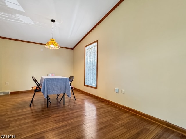 dining space featuring vaulted ceiling, ornamental molding, and hardwood / wood-style floors