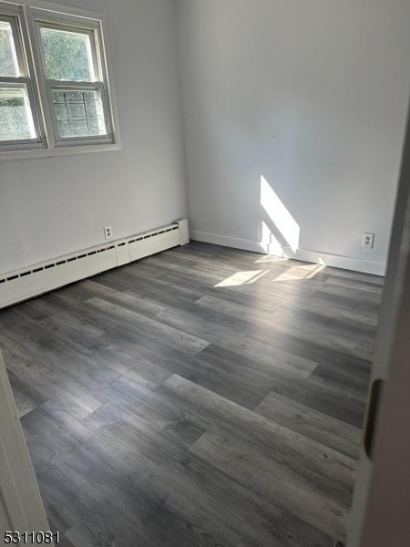 empty room featuring a baseboard radiator and dark hardwood / wood-style floors