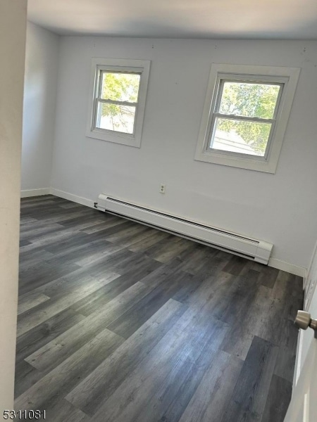 spare room with dark wood-type flooring and baseboard heating