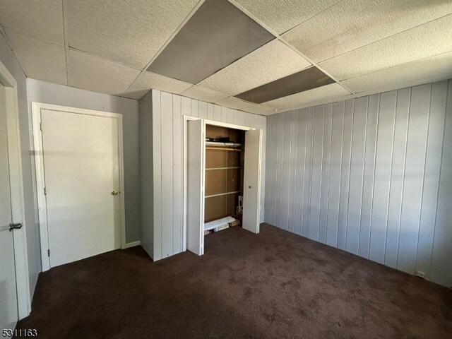 unfurnished bedroom with wood walls, a closet, and carpet floors