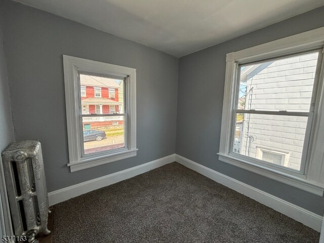 unfurnished room featuring radiator and carpet floors