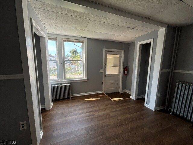 spare room featuring a paneled ceiling, dark hardwood / wood-style floors, and radiator heating unit