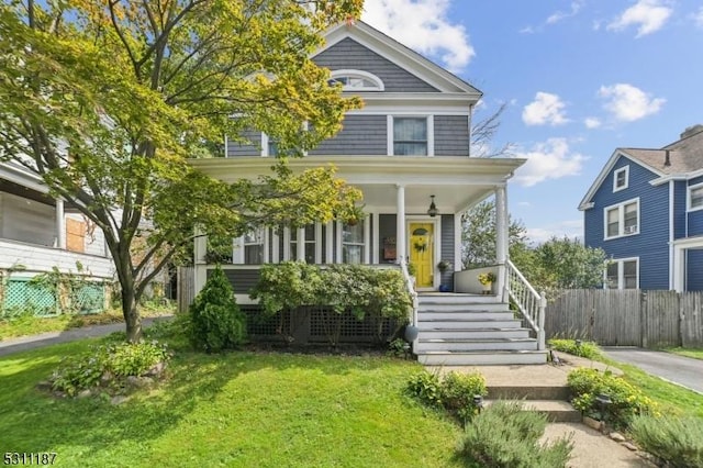 view of front facade featuring covered porch, a front lawn, and fence