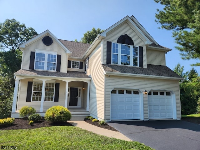 view of front of house featuring a garage, a porch, and a front lawn