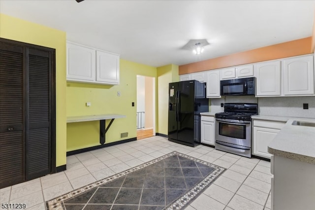 kitchen featuring black appliances, sink, light tile patterned floors, and white cabinets