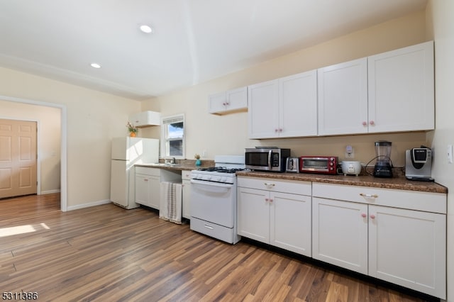 kitchen featuring dark wood-type flooring, white cabinets, and white appliances