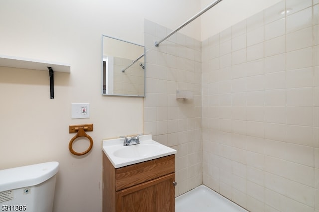 bathroom with toilet, vanity, and a tile shower