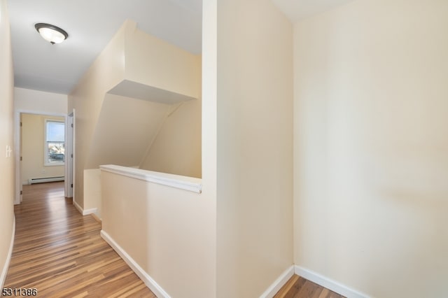 corridor with baseboard heating and light hardwood / wood-style floors