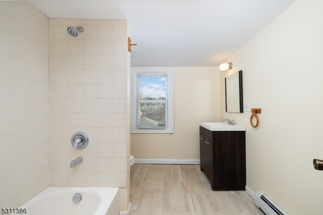 full bathroom featuring tiled shower / bath, hardwood / wood-style flooring, toilet, vanity, and baseboard heating