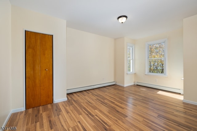 unfurnished room featuring baseboard heating and hardwood / wood-style flooring