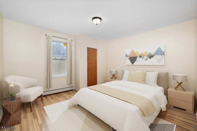 bedroom with light hardwood / wood-style floors and baseboard heating