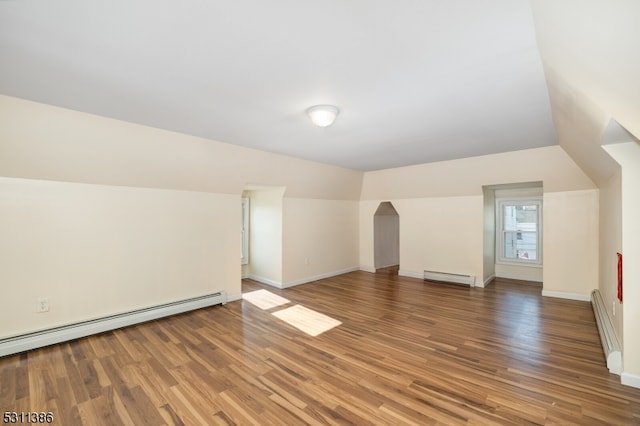 additional living space featuring vaulted ceiling, hardwood / wood-style flooring, and a baseboard heating unit