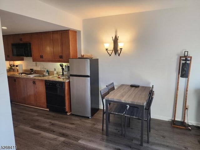 kitchen featuring black dishwasher, brown cabinetry, dark wood finished floors, and freestanding refrigerator