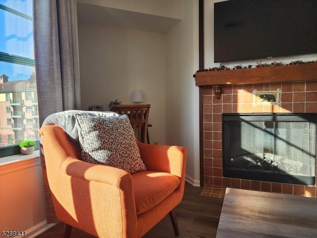 living area featuring a tiled fireplace, wood finished floors, and baseboards