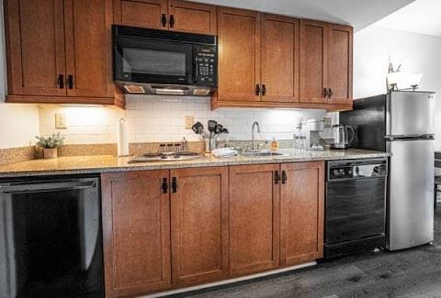 kitchen featuring tasteful backsplash, black appliances, light stone counters, sink, and dark wood-type flooring