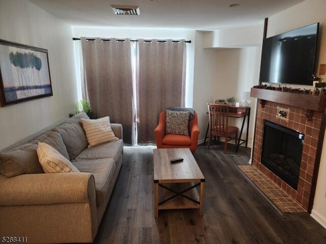 living room featuring dark wood-type flooring and a tile fireplace