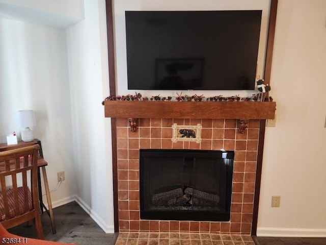 interior details featuring a tiled fireplace, wood finished floors, and baseboards