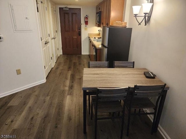 dining area featuring dark wood-type flooring, electric panel, and baseboards