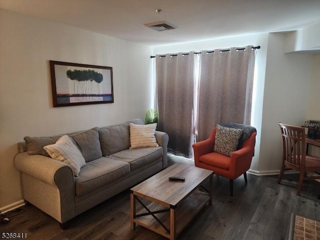 living room with baseboards, visible vents, and wood finished floors