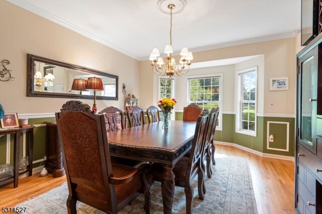 dining room featuring ornamental molding, light hardwood / wood-style flooring, and a notable chandelier