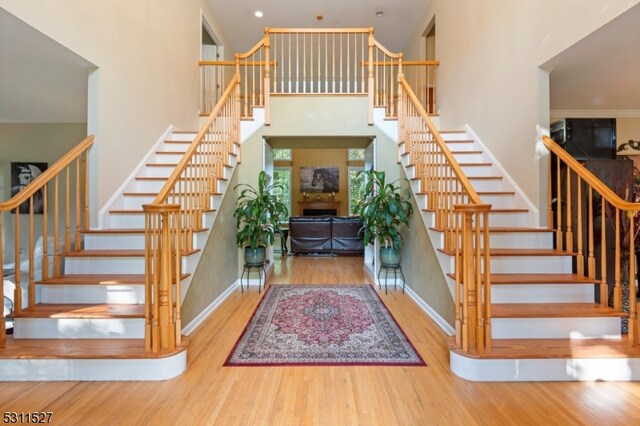 stairway with wood-type flooring and a high ceiling