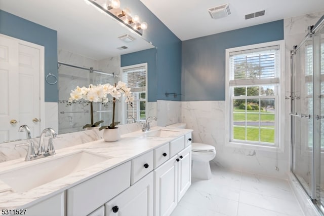 bathroom with vanity, toilet, tile walls, and a shower with door