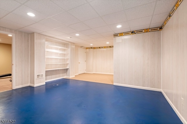 basement with built in shelves and a drop ceiling