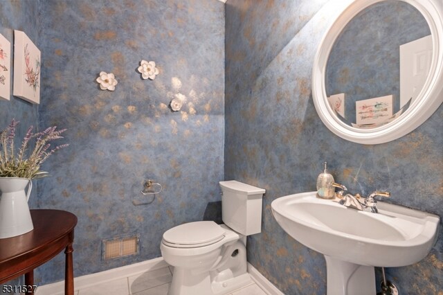 bathroom with toilet, sink, and tile patterned floors