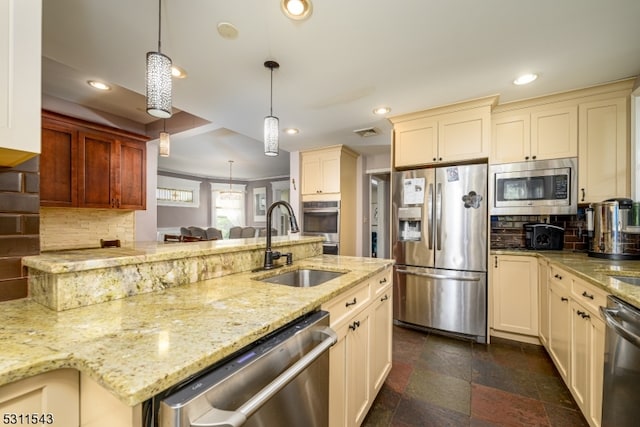 kitchen with pendant lighting, tasteful backsplash, sink, light stone countertops, and appliances with stainless steel finishes