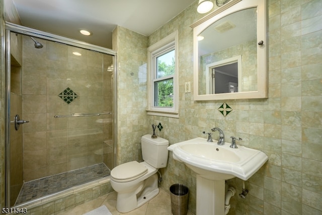 bathroom featuring a shower with door, tile walls, and toilet