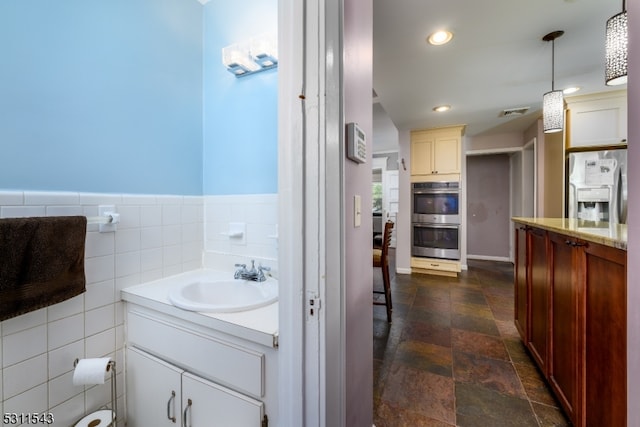 bathroom featuring vanity, backsplash, and tile walls