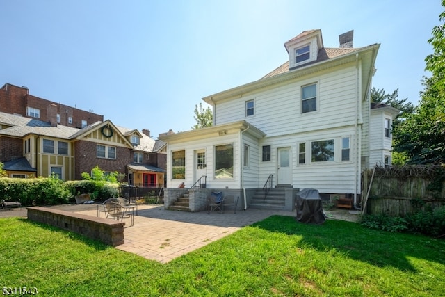 rear view of house featuring a lawn and a patio