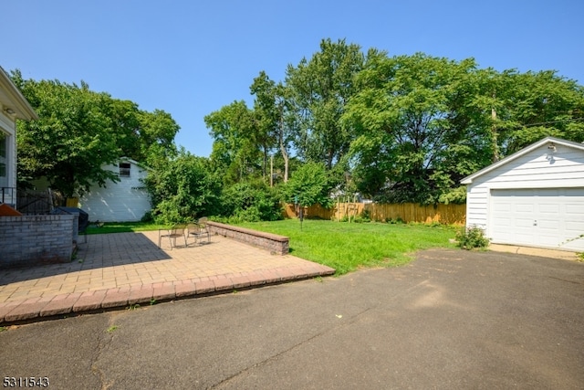 view of yard with an outdoor structure, a garage, and a patio