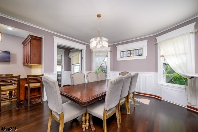 dining area with dark wood-type flooring, a notable chandelier, and crown molding