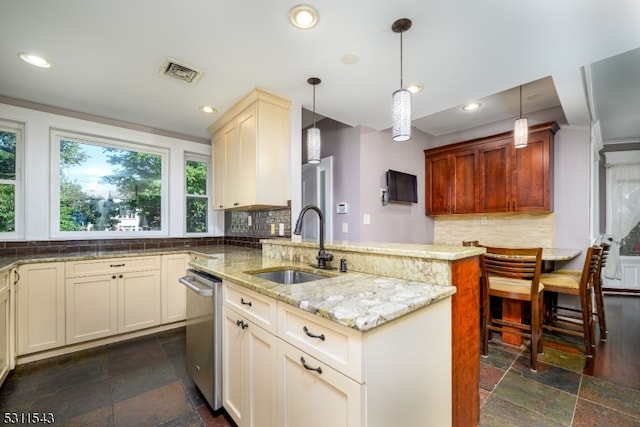 kitchen with light stone countertops, decorative light fixtures, sink, and decorative backsplash