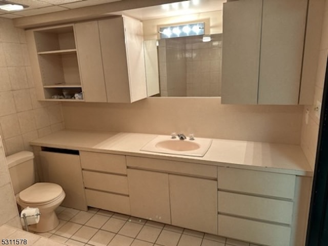 bathroom with vanity, toilet, tile patterned floors, and tile walls