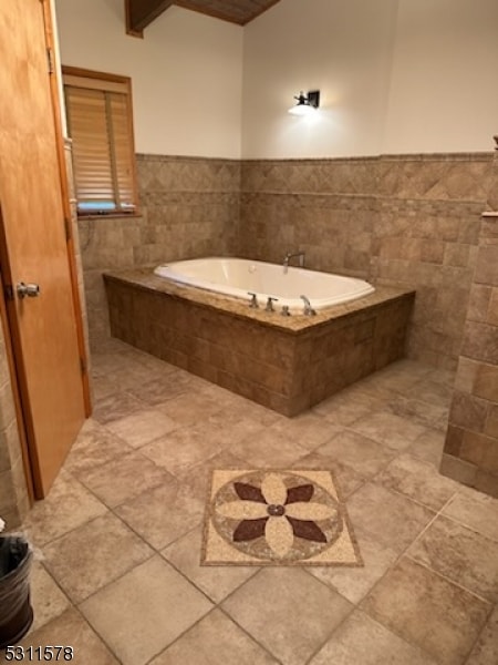 bathroom with tile walls and tiled tub