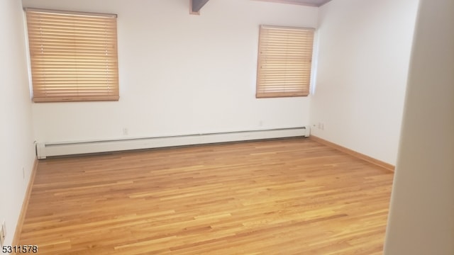 unfurnished room with baseboard heating and light wood-type flooring