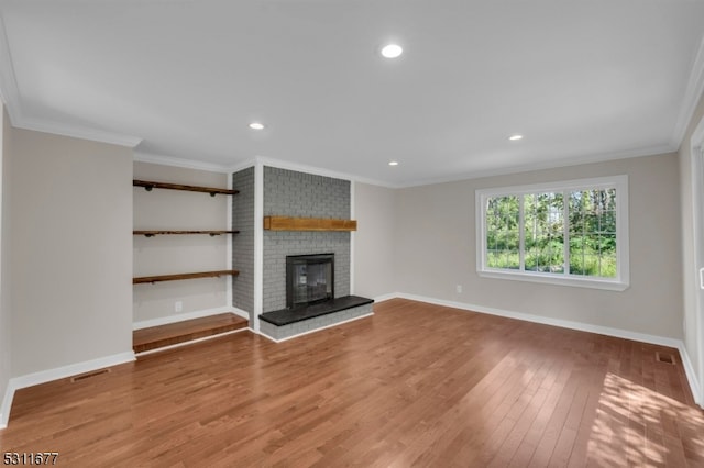 unfurnished living room featuring ornamental molding, wood-type flooring, and a fireplace