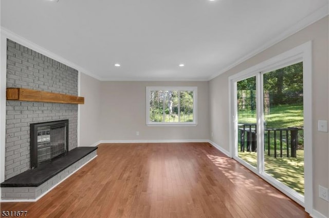unfurnished living room featuring crown molding, wood finished floors, a fireplace, baseboards, and recessed lighting