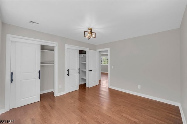 unfurnished bedroom featuring hardwood / wood-style floors and an inviting chandelier