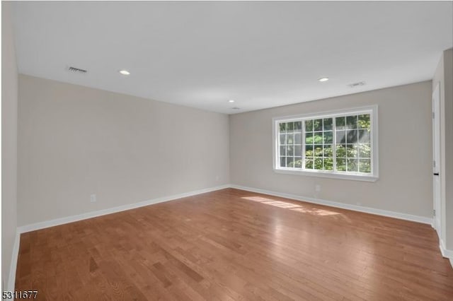 spare room with visible vents, baseboards, and wood finished floors