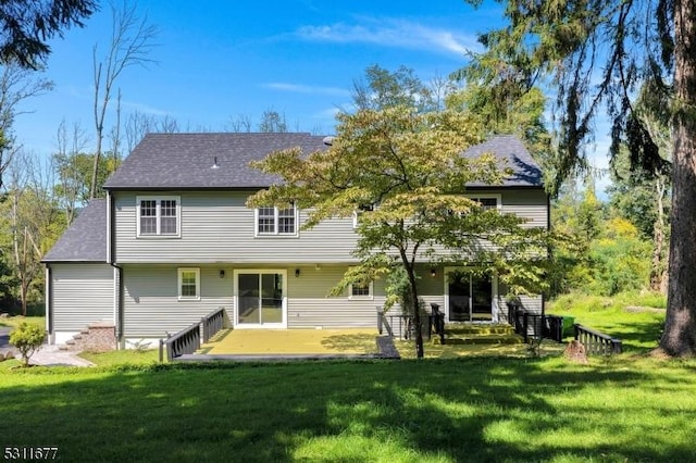 back of house with a lawn and a shingled roof