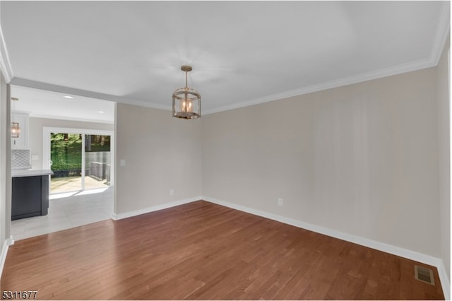 spare room featuring ornamental molding and light hardwood / wood-style flooring