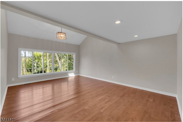 unfurnished room with hardwood / wood-style floors, a chandelier, and vaulted ceiling