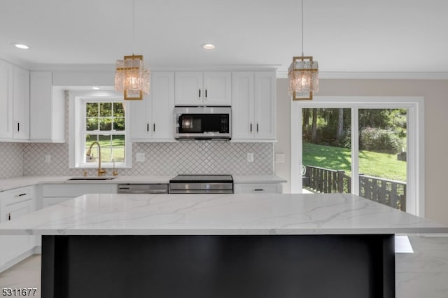 kitchen with a kitchen island, stainless steel appliances, a chandelier, and sink