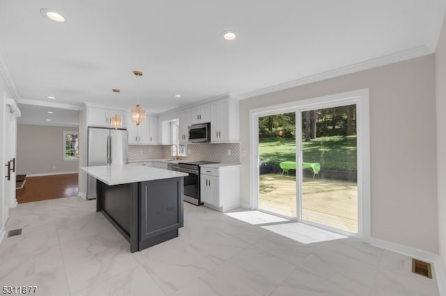 kitchen featuring a kitchen island, decorative light fixtures, stainless steel appliances, sink, and white cabinets