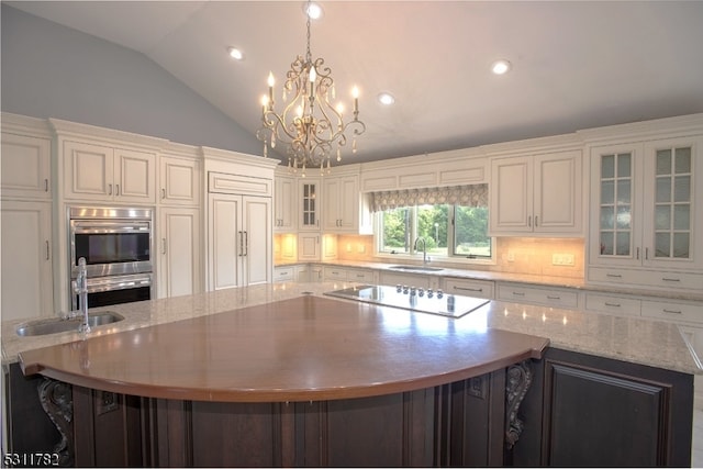 kitchen featuring a spacious island, sink, decorative light fixtures, white cabinets, and lofted ceiling