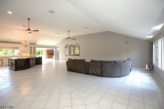 unfurnished living room with light tile patterned floors, ceiling fan with notable chandelier, lofted ceiling, and sink